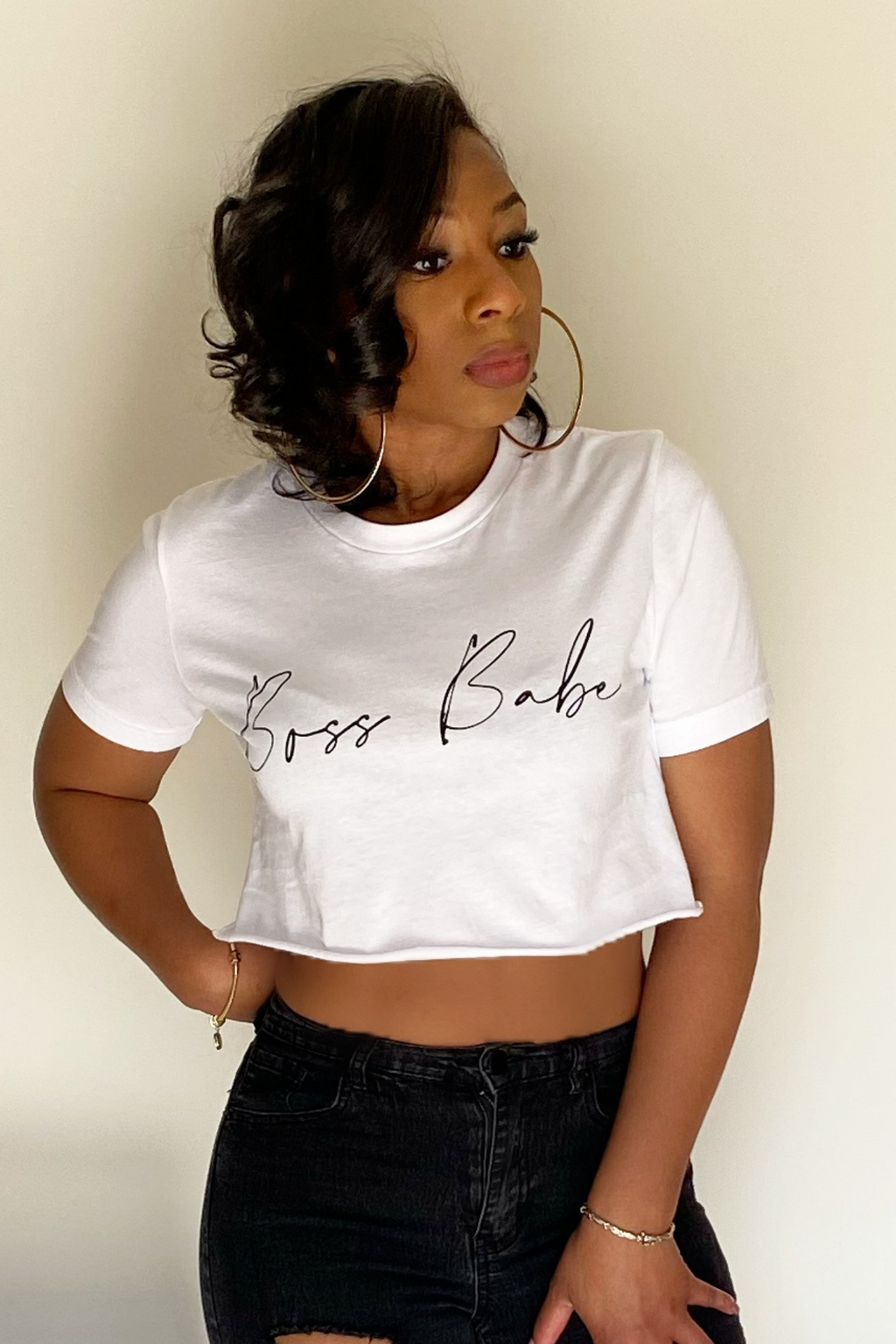 The front view of the whit short sleeved crop t-shirt. The t-shirt has the words boss babe written in black cursive letters across the middle. The shirt stops about 6 inches up from the belly button. The shirt was paired with black distressed jeans.