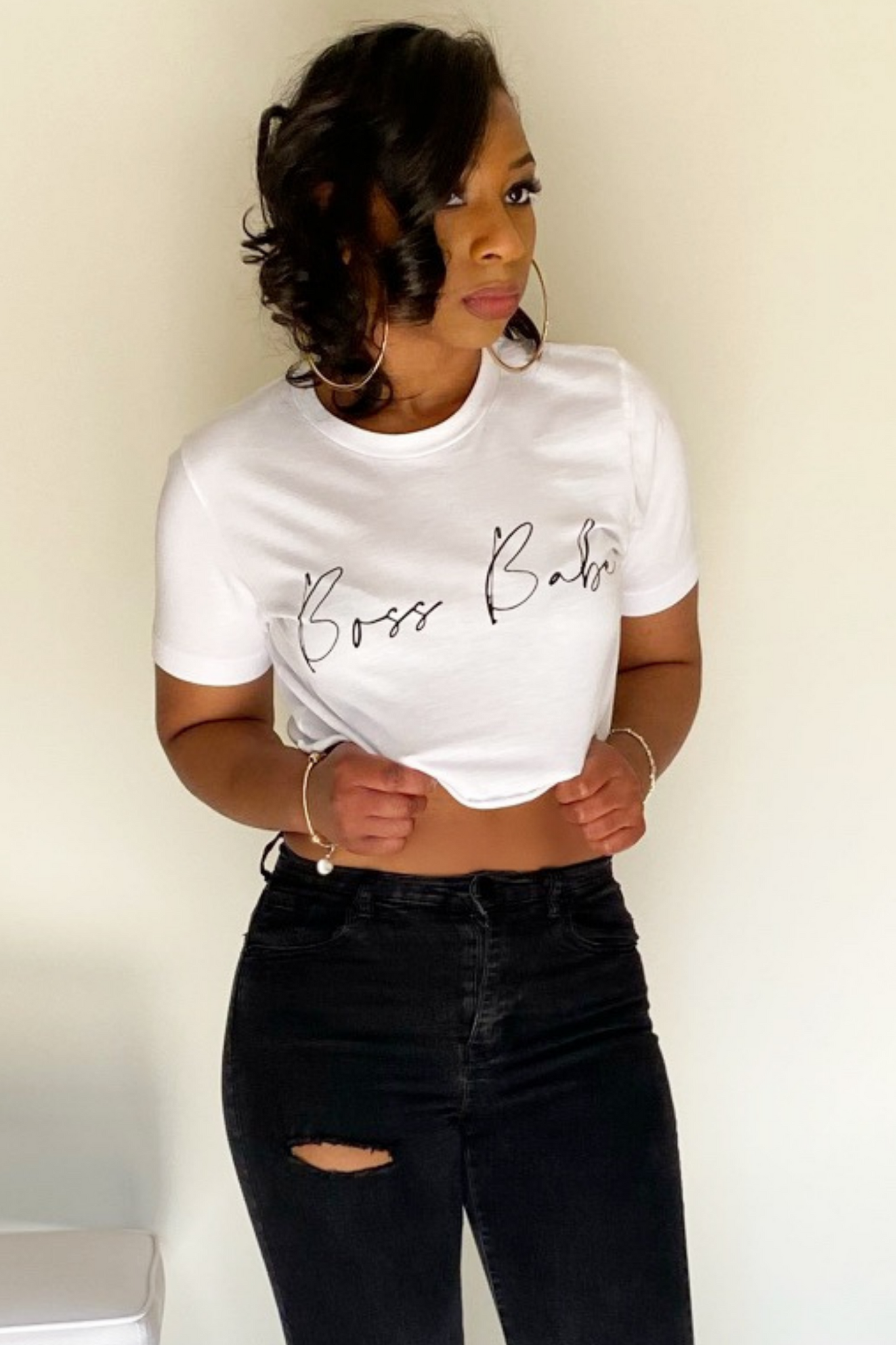 The front view of the whit short sleeved crop t-shirt. The t-shirt has the words boss babe written in black cursive letters across the middle. The shirt stops about 6 inches up from the belly button. The shirt was paired with black distressed jeans.