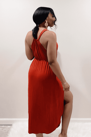 Back view of the orange midi dress with a deep cut neckline and spaghetti Straps.  Adjustable elastic waist with two thigh high side slits.