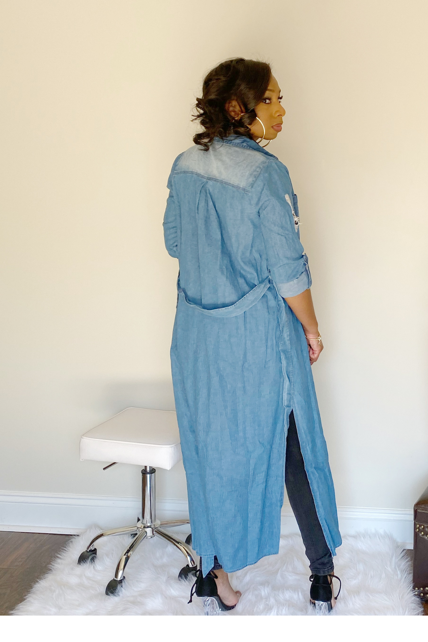 Back view of denim shirt that displays the removable denim strap belt that comes with the shirt. The side split of the shirt can be seen from the back view.